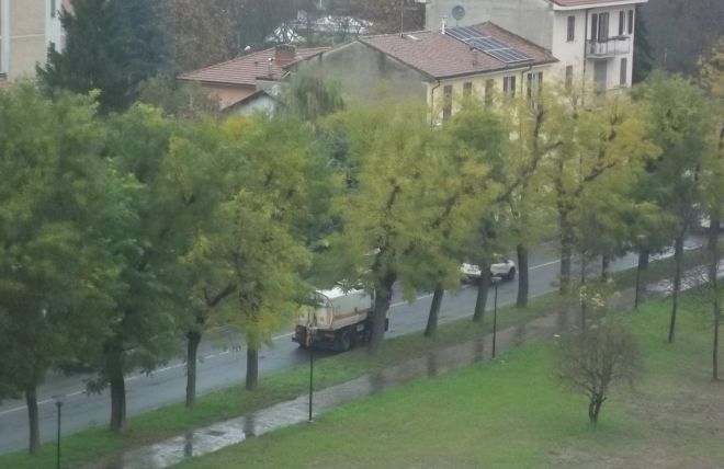 La macchina spazzatrice procede lentamente perché sta pulendo la strada, un'auto l'ha appena sorpassata