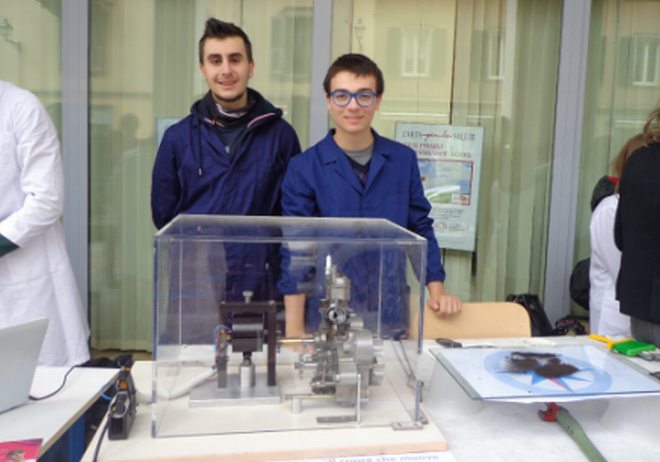 Alessandro Martini di 4 AM E Samuele Palumbo di 5 AM hanno suscitato la curiosità di grandi e piccini illustrando il funzionamento di un motore. Il progetto, presentato alla maturità del 2013 dall’ex alunno Davide Poggio, è stato assemblato mettendo insieme più pezzi meccanici tra cui il motorino di un trapano e quello di un ciclomotore, sacrificato sugli altari della scienza.     